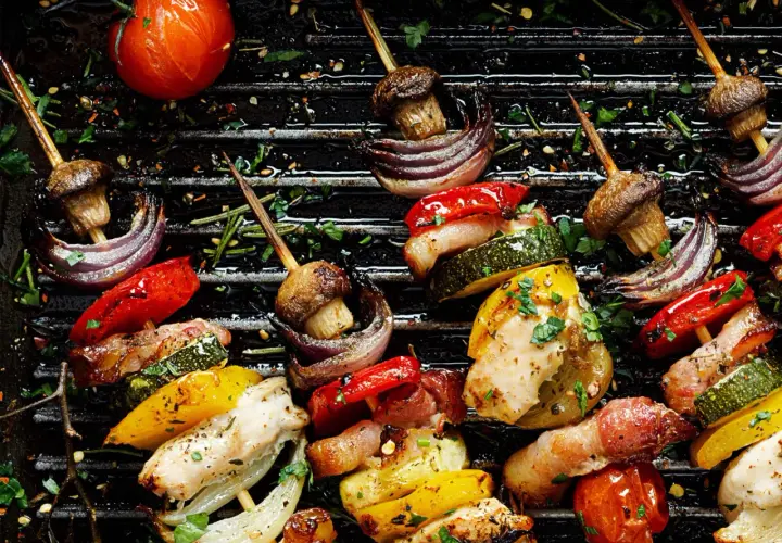 Brochettes de poulet et de legume bbq sur un grill, avec des poivrons, courgettes, oignons rouges, champignons et tomates.