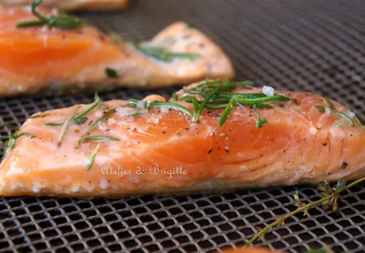 Filets de saumon sur une grille, assaisonnés de sel, poivre et romarin. Parfait pour une cuisson plancha à la bonne température.