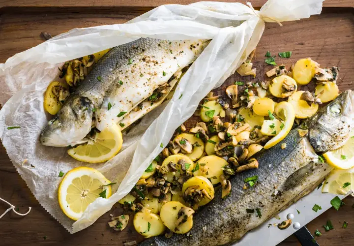 Deux bars en papillote au barbecue, accompagnés de pommes de terre et champignons, citron et persil.