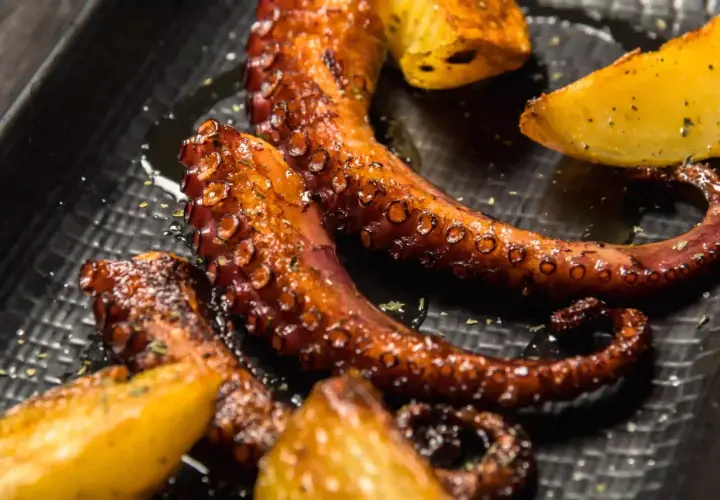 Tentacules de poulpe a la plancha, grillés à la perfection, servis avec des quartiers de pommes de terre dorées. Un délice croustillant et savoureux.