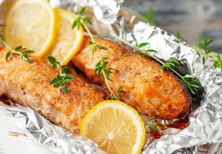 Deux pavés de poisson, cuits en papillote sur la plancha, ornés de rondelles de citron et de brins de thym frais.