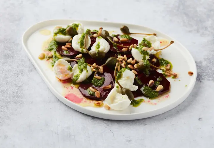 Salade de betterave fumée, mozzarella, pignons et câpres, arrosée d'une sauce verte.