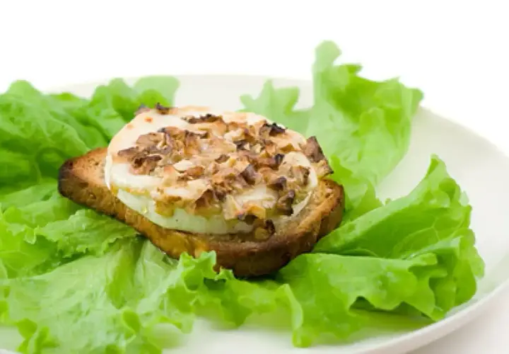 Tartine de chèvre chaud, garnie de noix, sur un lit de laitue fraîche. Un délice simple, comme un chevre au barbecue.