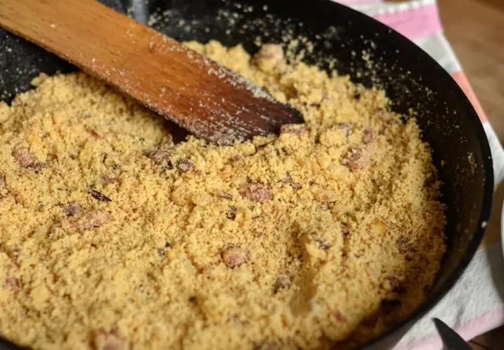 Préparation d'une recette de farine de maïs dans une poêle avec une spatule en bois.