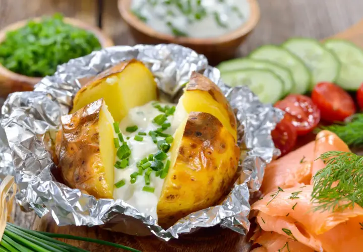 Pommes de terre à la braise, enveloppées dans du papier aluminium, garnies de crème et de ciboulette. Parfait pour le temps de cuisson.