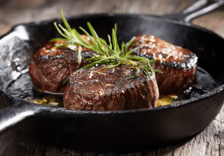 Trois tournedos saisis à la poêle, garnis de romarin frais. Une recette simple pour un plat savoureux.