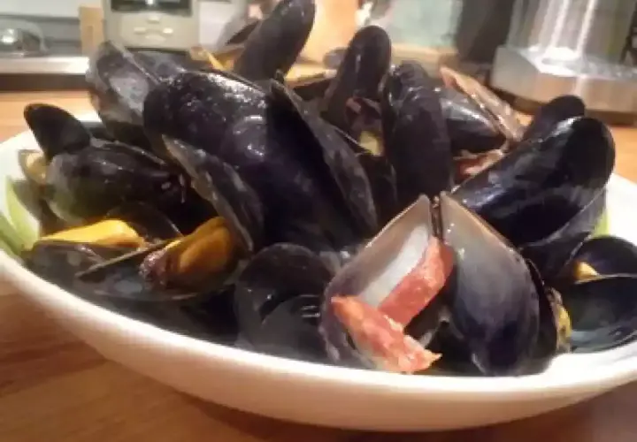 Un plat de moules poulette, fumantes et appétissantes, garnies de lardons croustillants. Un délice à partager.