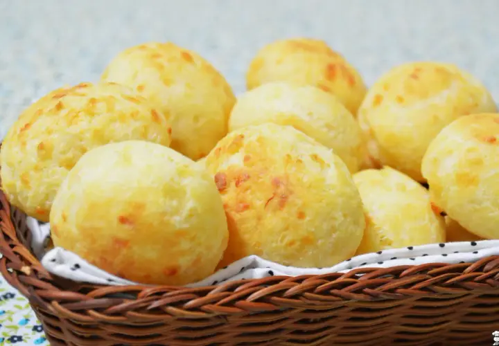 Un panier en osier déborde de délicieux pao de queijo dorés, parfaits pour un goûter.