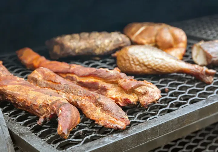 Plusieurs morceaux de filet de porc fumé, dorés et juteux, reposent sur une grille de barbecue, prêts à être dégustés.