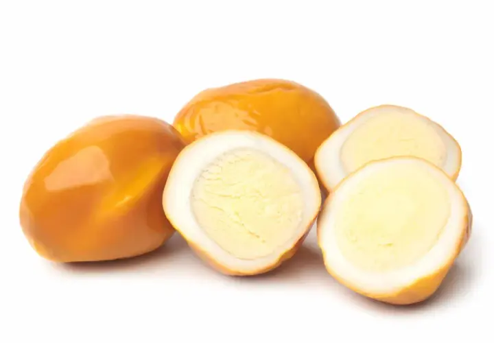 Œufs fumés entiers et coupés en deux, révélant un jaune d'œuf crémeux.