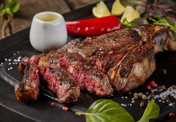 Une côte de bœuf parfaitement saisie, juteuse et rosée, prête pour la dégustation. La cuisson est idéale pour ce plat.