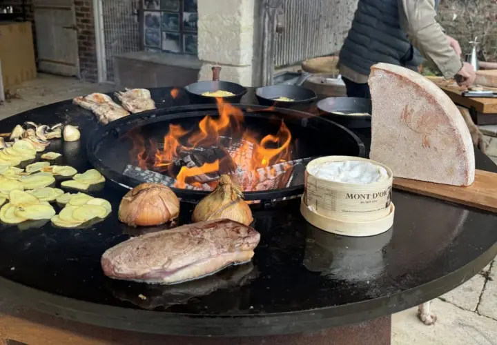 Préparation d'une recette brasero hiver : viande, pommes de terre, oignons, champignons et Mont d'Or fondent sur le feu.