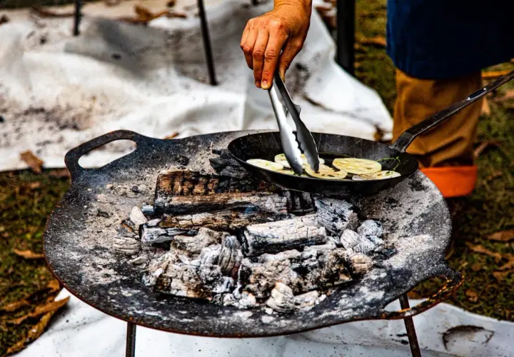 Cuisson de rondelles de lotus dans une poêle sur un feu de bois. La température du barbecue est parfaite pour cette cuisson.