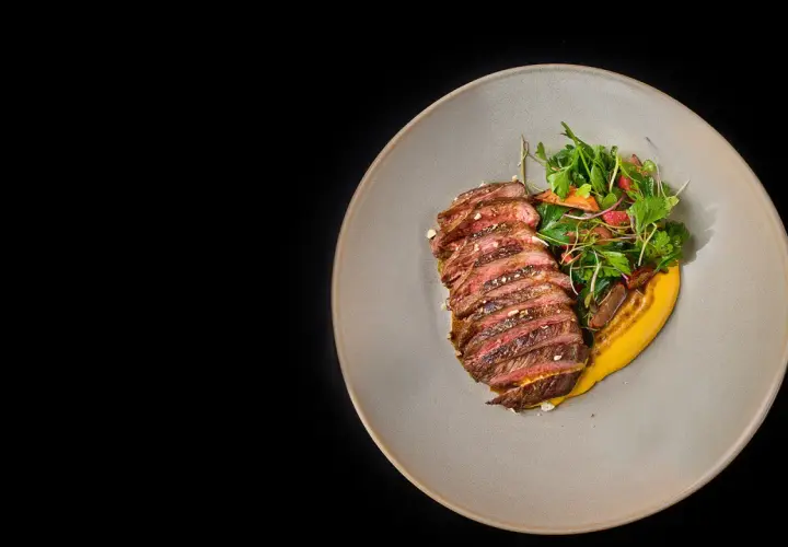 Tranches de rumsteak d'agneau grillé, servies avec une purée de courge et une salade fraîche.