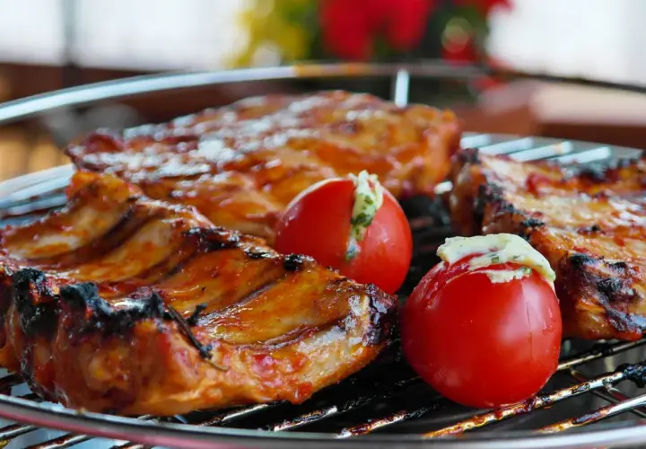 Côtelettes de porc grillées, savourant la qualité de la viande espagnole, accompagnées de tomates farcies.