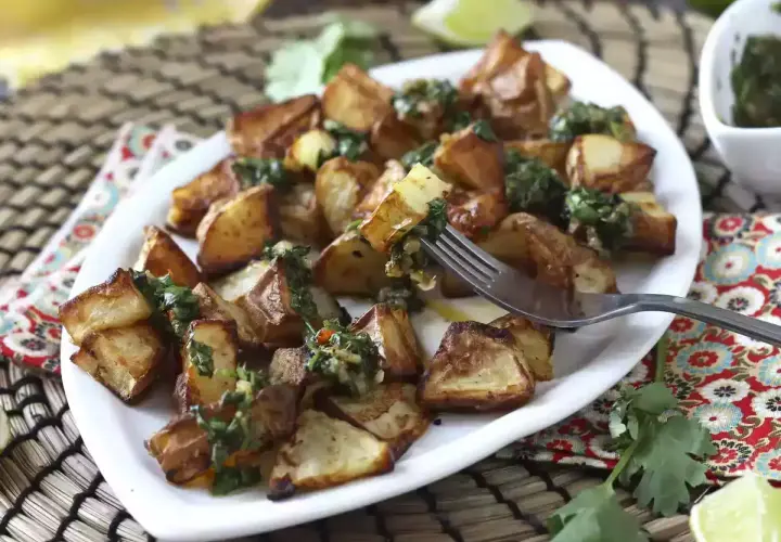 Pommes de terre rôties, garnies d'une sauce verte fraîche, prêtes à être dégustées. Un délice parfait pour un repas d'été, comme un coulommier au barbecue.