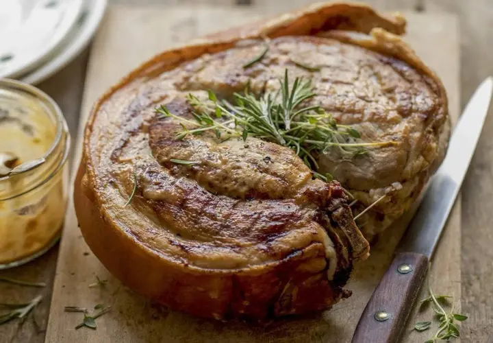Rouelle de porc au barbecue, dorée et savoureuse, garnie de romarin et de thym. Un délice à partager !