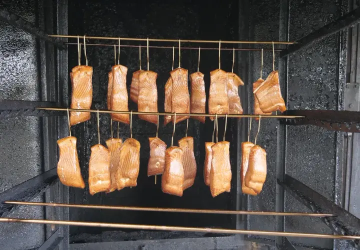 Filets de saumon suspendus dans un fumoir, prêts pour le fumage à froid. Le saumon est une excellente viande à fumer à froid.