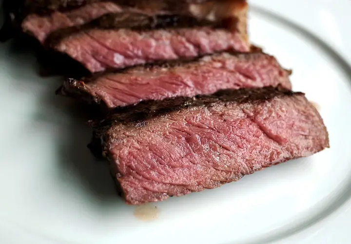 Tranches de bœuf bleu blanc belge, juteuses et saignantes, sur une assiette blanche.