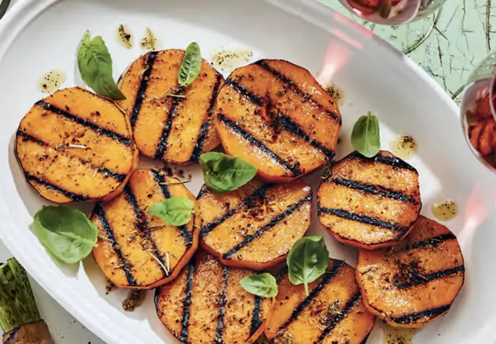 Tranches de courge au barbecue, grillées et assaisonnées, garnies de feuilles de basilic frais. Un délice estival !
