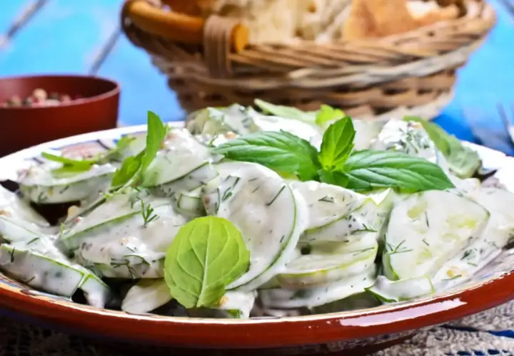 Salade fraîche de concombre à la crème, garnie de menthe et d'aneth. Parfait pour accompagner un concombre au barbecue.