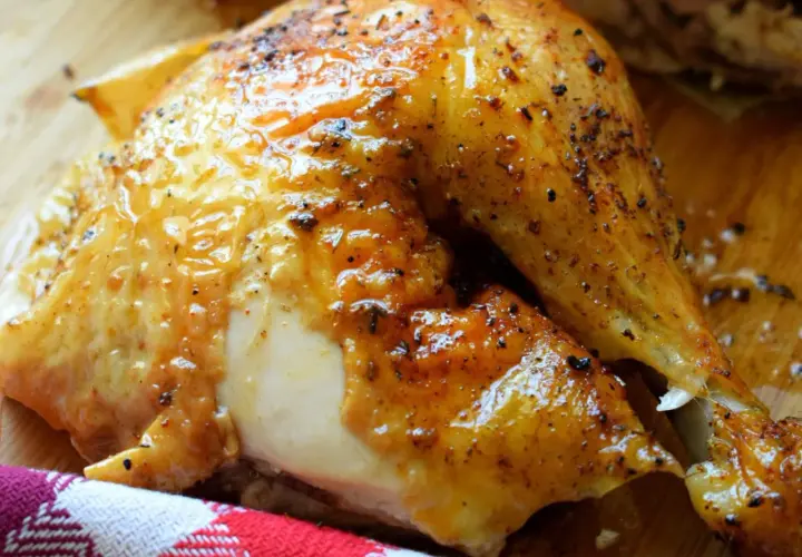 Un délicieux demi poulet BBQ, la peau dorée et brillante, prêt à être dégusté.