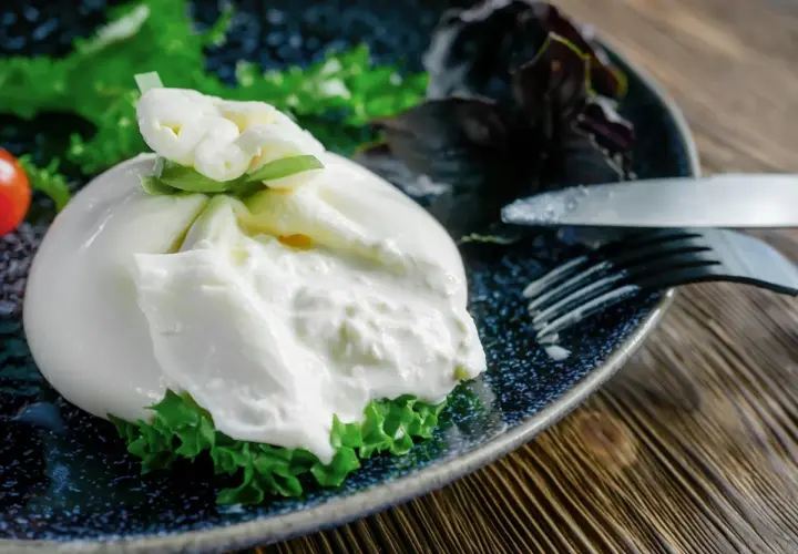 Une burrata fumée onctueuse sur un lit de verdure, prête à être dégustée. Une recette simple et savoureuse.