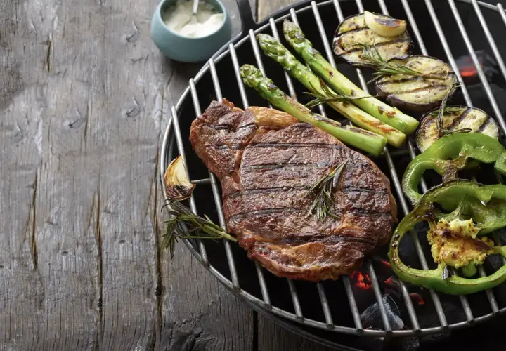 Un steak savoureux, des asperges, des aubergines et des poivrons verts sur un barbecue. Parfait pour savoir que faire cuire au barbecue.