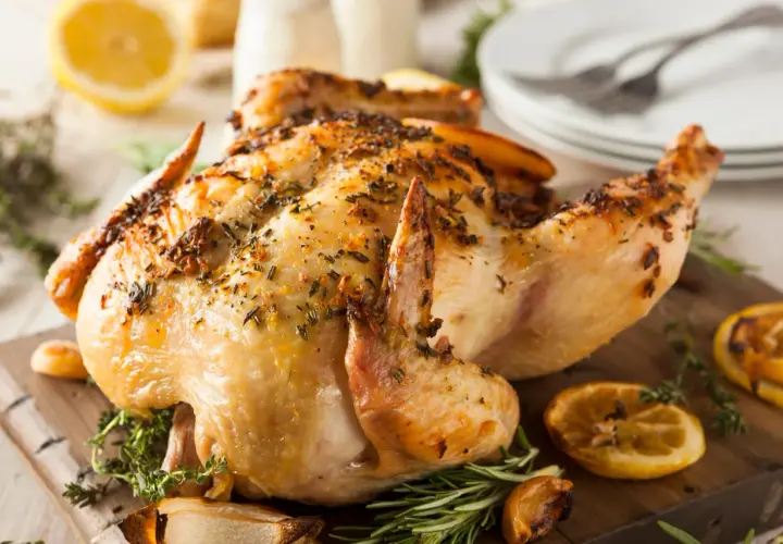 Un poulet entier au barbecue, doré et savoureux, garni d'herbes et de quartiers de citron grillés. Un délice pour les papilles !