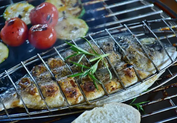 Dorade grillée sur barbecue Weber, avec tomates et courgettes. Le temps de cuisson est parfait pour ce plat savoureux.