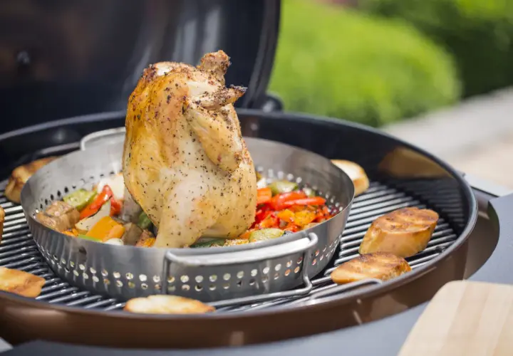 Un poulet rôti sur un barbecue, avec des légumes colorés et des tranches de pain grillé. Le poulet est assaisonné et semble juteux, prêt à être dégusté.