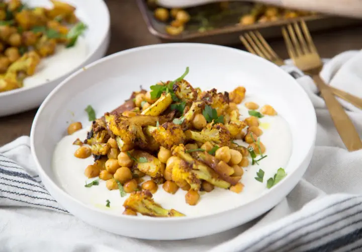 Chou-fleur rôti aux épices, pois chiches et sauce crémeuse. Un délice de chou fleur barbecue, garni de persil frais.