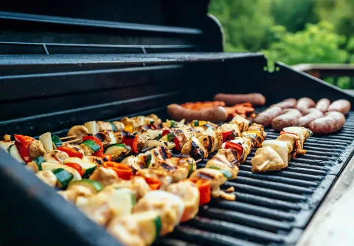 Brochettes de poulet et légumes, saucisses en train de cuire sur un barbecue à gaz.