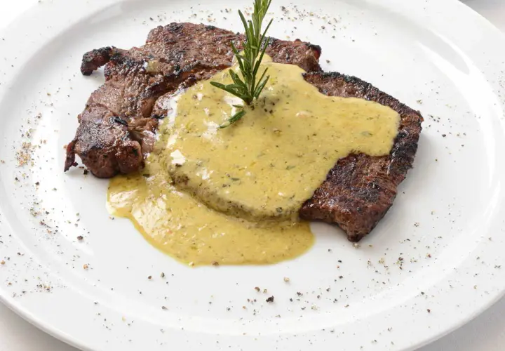 Un steak grillé, nappé d'une sauce crémeuse et garni d'une branche de romarin. Parfait pour accompagner une sauce pour entrecôte au barbecue.