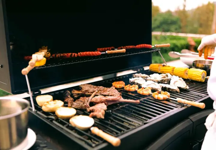 Viande, crevettes, huîtres et maïs sur un barbecue à gaz. Le fumage barbecue gaz ajoute une saveur délicieuse.