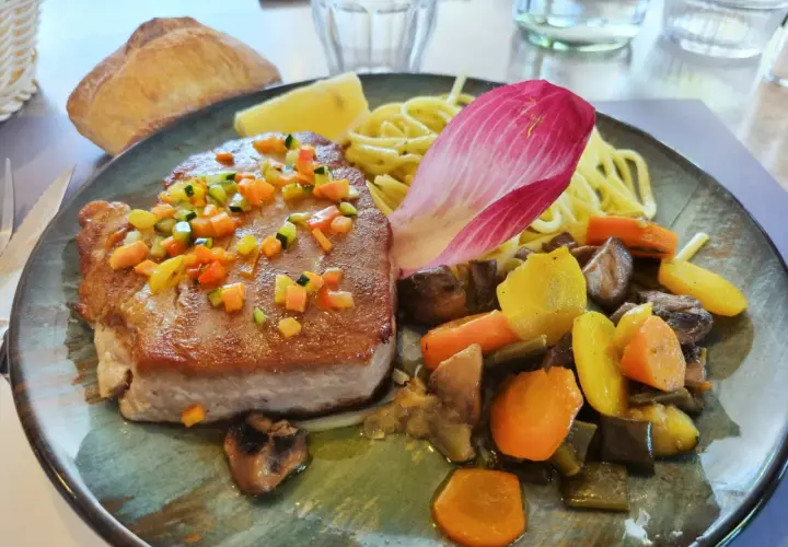 Pavé de thon poêlé, garni de dés de légumes croquants, servi avec des pâtes, des légumes racines et une feuille de chicorée. Une recette savoureuse.