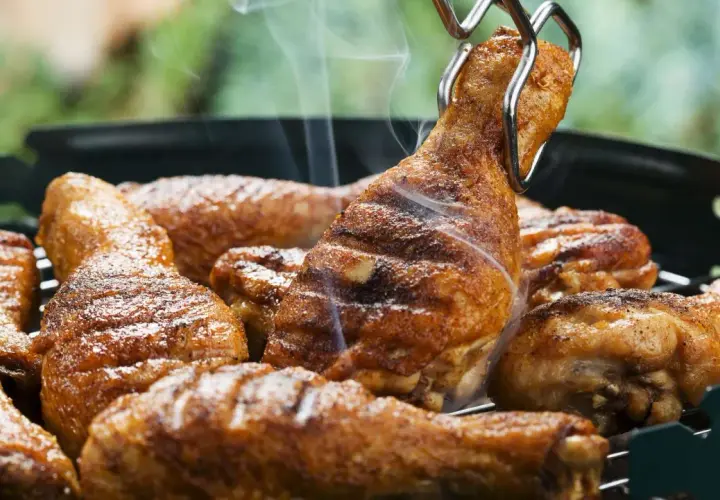 Des pilons de poulet grillés, savamment préparés avec une marinade pilon de poulet barbecue, dégagent une fumée appétissante sur le barbecue.