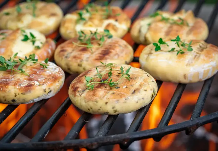 Ronds de halloumi au barbecue, dorés et parsemés de thym frais, grésillant sur les braises ardentes.