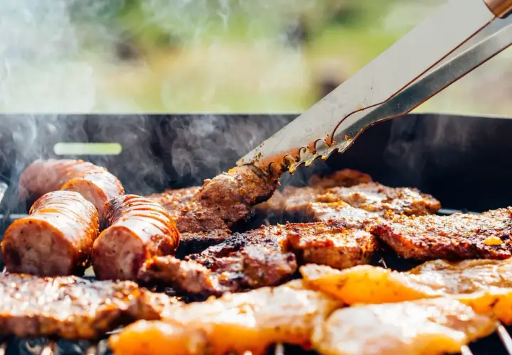 Des saucisses et des morceaux de viande au barbecue, fumants et grillés à la perfection. Un délice estival.