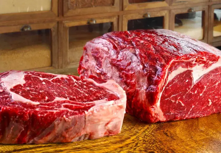 Deux pièces de viande rouge vif, un steak épais et un rôti, sur une planche en bois. Ce filet de bœuf promet un repas savoureux.