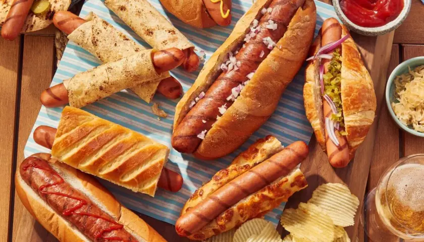 Un festin de hot-dogs pour un barbecue : pains variés, garnitures et chips.