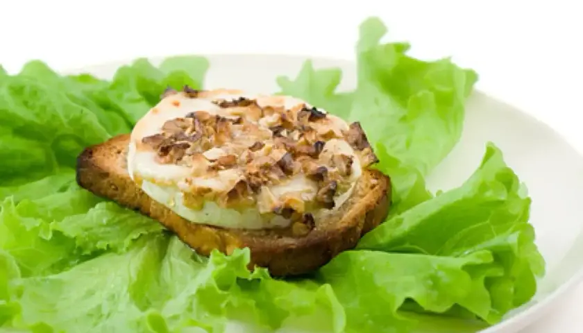 Tartine de chèvre chaud, garnie de noix, sur un lit de laitue fraîche. Un délice simple, comme un chevre au barbecue.