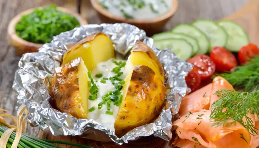 Pommes de terre à la braise, enveloppées dans du papier aluminium, garnies de crème et de ciboulette. Parfait pour le temps de cuisson.