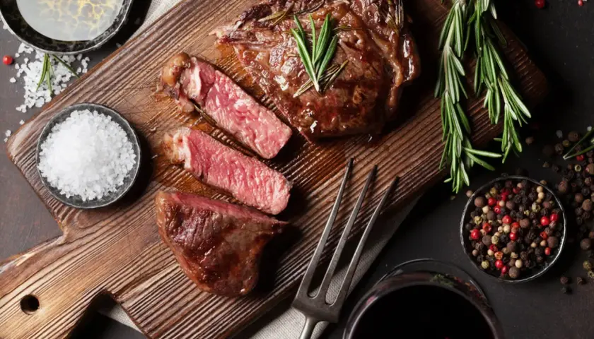 Un steak juteux, tranché, avec du romarin, du sel et du poivre. Une image parfaite pour apprendre comment fumer de la viande.