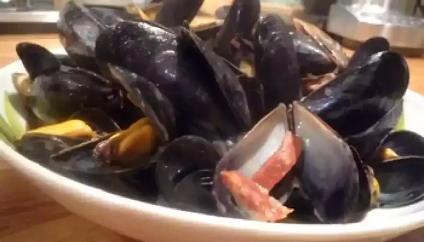 Un plat de moules poulette, fumantes et appétissantes, garnies de lardons croustillants. Un délice à partager.