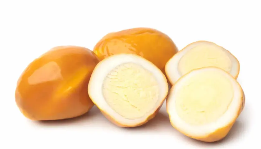 Œufs fumés entiers et coupés en deux, révélant un jaune d'œuf crémeux.