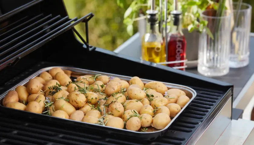 Un plateau de pommes de terre nouvelles assaisonnées d'herbes, prêtes pour le barbecue.