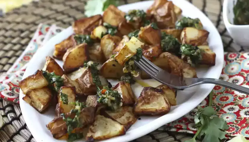 Pommes de terre rôties, garnies d'une sauce verte fraîche, prêtes à être dégustées. Un délice parfait pour un repas d'été, comme un coulommier au barbecue.