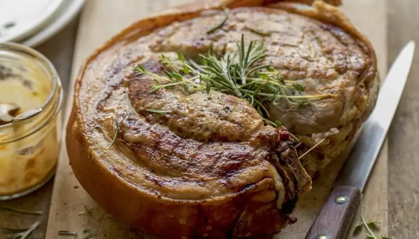 Rouelle de porc au barbecue, dorée et savoureuse, garnie de romarin et de thym. Un délice à partager !