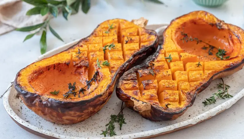 Butternut au barbecue, coupé en deux, grillé et parsemé de thym frais. La chair orangée est tendre et caramélisée.